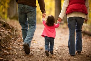 Girl walking in woods, holding parents hands